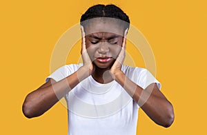 African American Woman Covering Ears Suffering From Otitis, Yellow Background