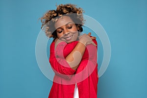 African american woman with curly hair hugging herself