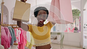 African american woman customer smiling confident holding shopping bags at clothing store