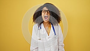 African american woman doctor angry screaming over isolated yellow background