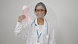 African american woman doctor holding breast cancer awareness pink ribbon over isolated white background