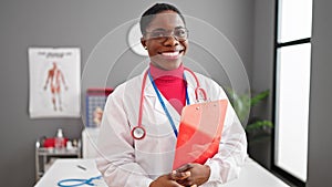 African american woman doctor smiling confident holding medical report at clinic