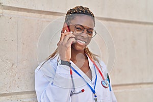 African american woman doctor smiling confident talking on smartphone at hospital