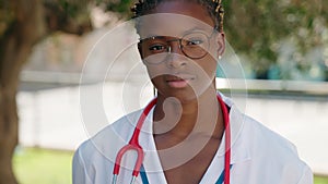 African american woman doctor standing with serious expression at park