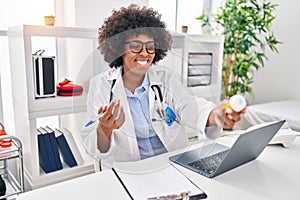 African american woman doctor using laptop prescribe pills at clinic