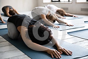 African American woman doing Balasana exercise at group yoga lesson