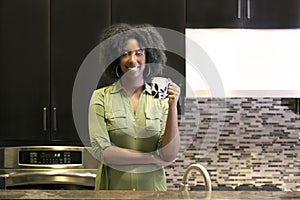 African American Woman Drinking Coffee or CBD Tea in a Kitchen