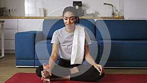 African american woman drinking water after workout at home on yoga mat