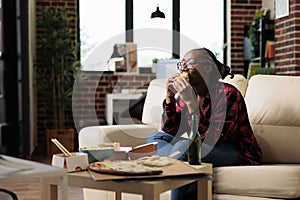 African american woman eating burger from fast food delivery