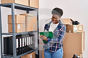 African american woman ecommerce business worker writing on clipboard at office