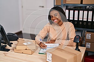African american woman ecommerce business worker writing on clipboard at office