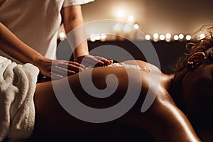 African-american woman enjoying salt scrub massage at spa