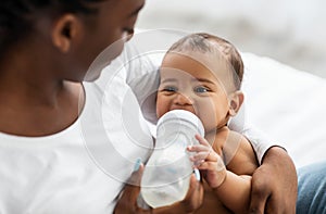 African American woman feeding her child from baby bottle photo