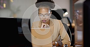 African American woman focuses intently on her business laptop screen at the office