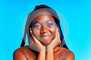 african american woman with gorgeus bright color make up feels proud and self confident in blue wall studio background