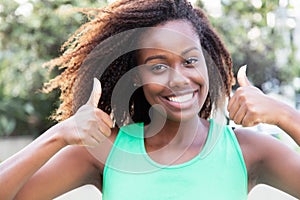 African american woman in a green shirt showing both thumbs