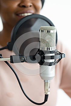 African American woman with headphones and a microphone recording a podcast in a recording studio