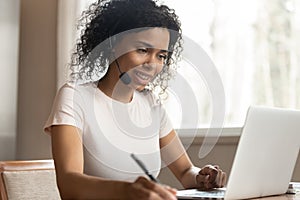 African American woman in headphones watch webinar on laptop