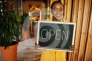 African american woman hold open welcome sign board in modern cafe coffee shop ready to service, restaurant, retail store, small
