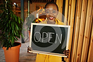 African american woman hold open welcome sign board in modern cafe coffee shop ready to service, restaurant, retail store, small