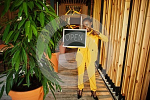 African american woman hold open welcome sign board in modern cafe coffee shop ready to service, restaurant, retail store, small