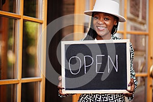 African american woman hold open welcome sign board in modern cafe coffee shop ready to service, restaurant, retail store, small