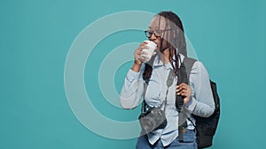 African american woman holding coffee cup and backpack