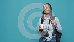 African american woman holding coffee cup and backpack