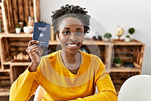 African american woman holding deutchland passport sitting on table at home photo