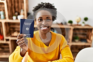 African american woman holding deutchland passport sitting on table at home photo