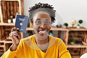 African american woman holding deutchland passport sitting on table at home photo