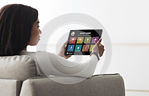 African american woman holding digital pad with smart house app