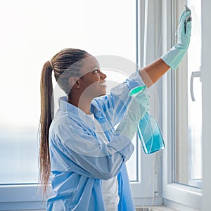 African american woman housekeeper cleaning windows at apartment