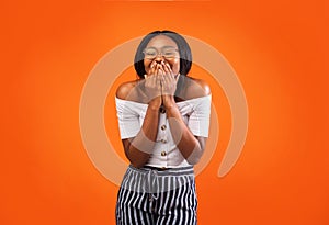African American Woman Laughing Covering Mouth Standing Over Orange Background