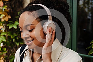 African american woman listening to music with headphones outdoors