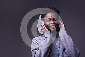 An African-American woman listening to music with headphones. A young woman wearing headphones smiles, looks directly