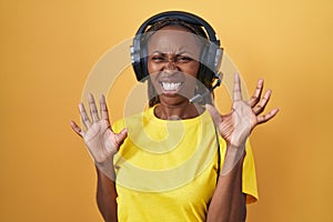 African american woman listening to music using headphones afraid and terrified with fear expression stop gesture with hands,