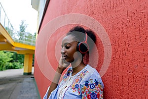 African American woman listens to music with headphones on the street