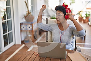 African american woman listneing to music sitting on table at home terrace