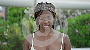 African american woman looking down with serious expression at park