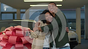 African American woman man happy millennial family couple buyers customers showing to camera key of new car present