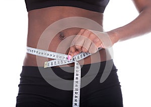 African American woman measuring waist with tape