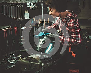 African american woman mechanic polishing motorcycle fuel tank