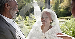 African american woman officiating wedding ceremony of senior biracial couple in garden, slow motion