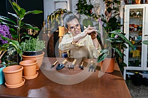 African American woman owner an ornamental garden with assistant using chart board to check the plants on a shelf in a