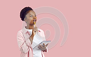 African American woman on pink copy space background thinking and writing in notebook