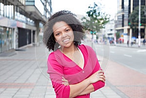 African american woman in pink shirt with crossed arms in the city
