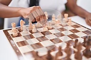 African american woman playing chess game sitting on table at home