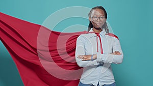 African american woman posing as superhero with red flying cape