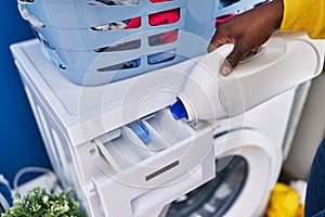 African american woman pouring detergent on washing machine at laundry room